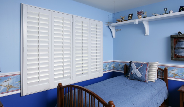 Large plantation shutters covering window in blue kids bedroom in Bluff City 